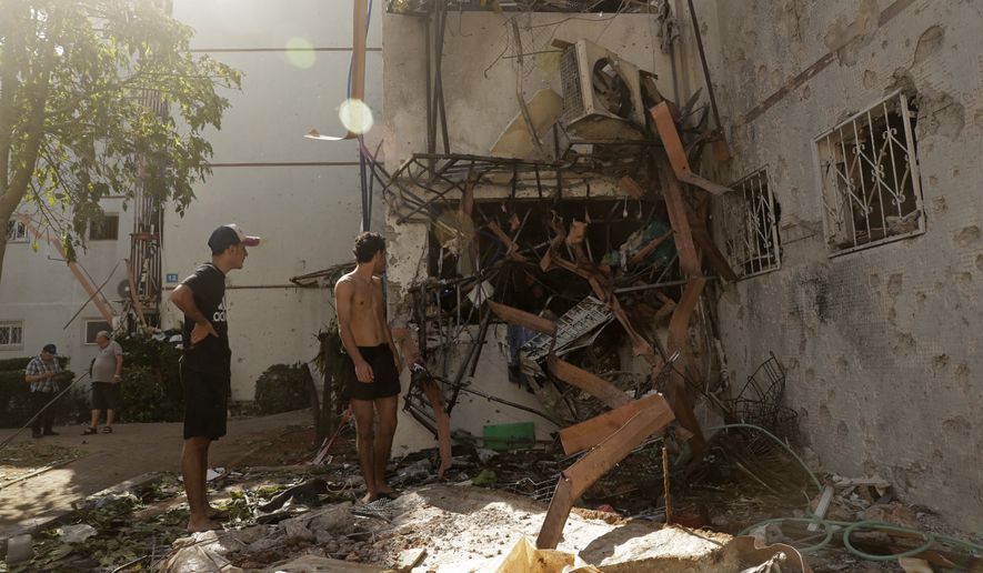People look at a residential building after it was hit by a rocket fired from the Gaza Strip, in Ashdod, southern Israel, Monday, May 17, 2021. (AP Photo/Maya Alleruzzo)