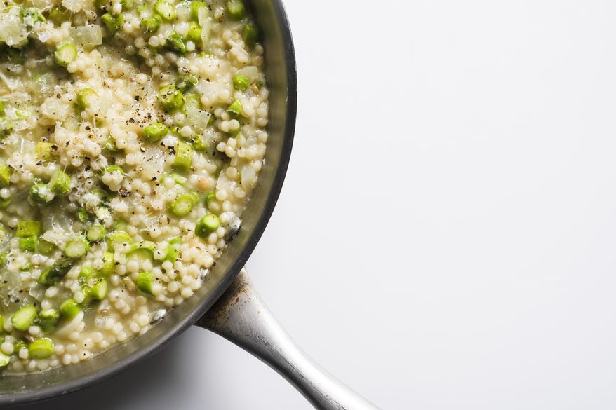 This image released by Milk Street shows a recipe for couscous risotto with asparagus. (Milk Street via AP)