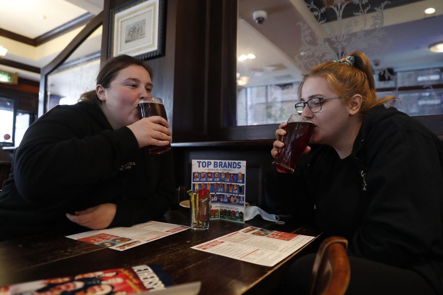 Libby Jones, right, with her colleague Shannon Maiden, both nurses from Great Ormond Street hospital who have just finished an overnight shift, have a pint of cider at the Shakespeare's Head pub, which will be reopening for the first time to serve indoor customers since the end of the latest coronavirus lockdown, in London, Monday, May 17, 2021. (AP Photo/Alastair Grant)