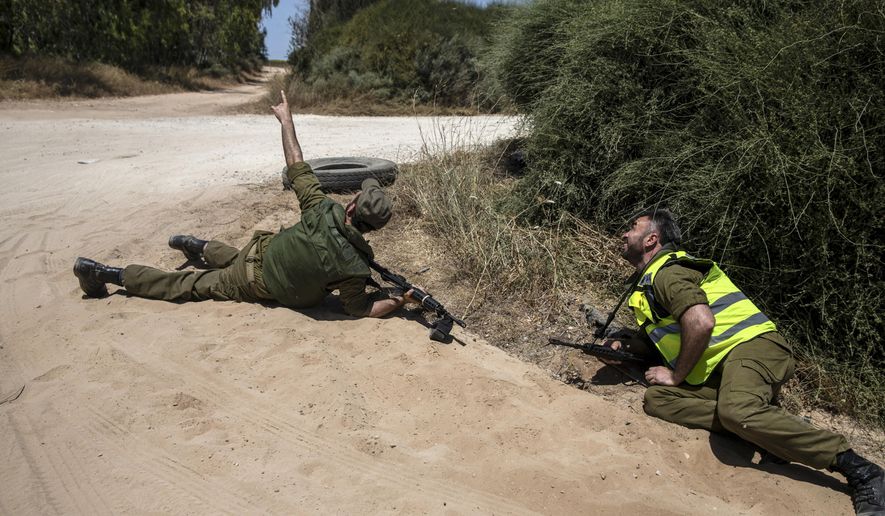 Israeli soldiers take cover on the ground as a siren sounds a warning of incoming rockets fired from the Gaza Strip, near the Israeli-Gaza border, in southern Israel, Monday, May 17, 2021. (AP Photo/Heidi Levine)