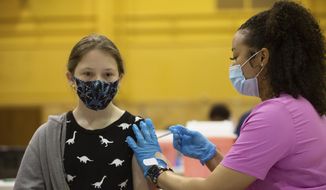 Twelve-year-old Jasic Helvey recieves a Pfizer COVID-19 vaccine by Shaunee Darrough, a nurse with TrueCare Nursing, Monday, May 17, 2021,  inside Topeka High&#x27;s gymnasium as part of a clinic with Topeka Public Schools USD 501.  (Evert Nelson/The Topeka Capital-Journal via AP)