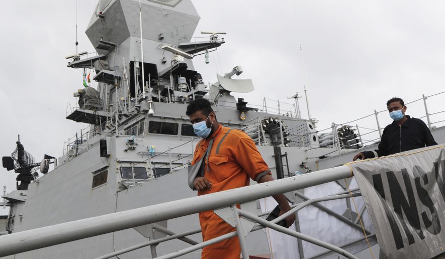 People rescued by the Indian navy from a barge that sank in the Arabian sea walk out from Indian naval ship INS Kochi in Mumbai, India, Wednesday, May 19, 2021. The barge carrying personnel deployed for offshore drilling sank off Mumbai as a deadly cyclone blew ashore this week. (AP Photo/Rajanish Kakade)