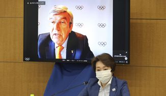 International Olympic Committee (IOC) President Thomas Bach delivers an opening speech on a screen at a meeting of the IOC Coordination Commission for the Tokyo 2020 Olympics in Tokyo on Wednesday, May 19, 2021, while Tokyo 2020 Olympics organizing committee President Seiko Hashimoto listens. Bach, Hashimoto, Japanese Olympic Minister Tamayo Marukawa and Tokyo Gov. Yuriko Koike attended a three-day meeting. (Yoshikazu Tsuno/Pool Photo via AP)