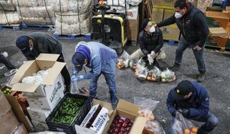 Fabian Arias, a Lutheran pastor with St. Peter&#39;s Church in Manhattan, center right, coordinates with volunteers as they prepare food delivery donations at a produce wholesaler, Friday, May 8, 2020, in the Bronx borough of New York. (AP Photo/John Minchillo, File)
