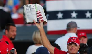 A Trump supporter lifts a Bible at a President Donald Trump campaign rally in Gastonia, N.C., Wednesday, Oct. 21, 2020. (AP Photo/Nell Redmond)
