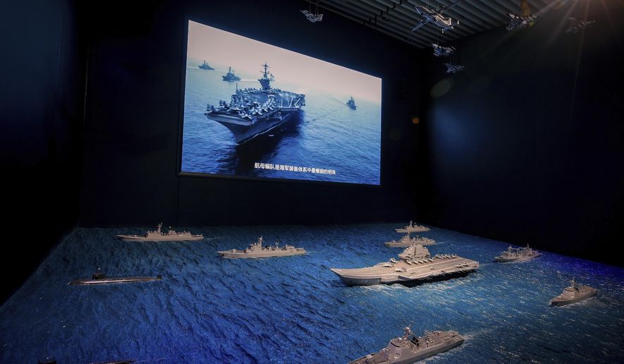In this Aug. 1, 2019, file photo, a TV screen showing the U.S. Navy fleet sail in formation near the models of Liaoning aircraft carrier with navy frigates and submarines on display at the military museum in Beijing. China on Wednesday, May 19, 2021, protested the latest passage by a U.S. Navy ship through the Taiwan Strait, calling it a provocation that undermined peace and stability in the region. (AP Photo/Andy Wong, File)