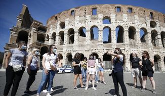 Tourists wear face masks to curb the spread of COVID-19 as they listen to a tour guide outside the ancient Colosseum, in Rome, Friday, May 21, 2021. The easing of travel restrictions this week have favored travel and tourism. (Cecilia Fabiano/LaPresse via AP) ** FILE **