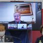 In this May 21, 2021, file photo, CEO of the Tokyo 2020 Toshiro Muto, left, and President of the Tokyo 2020 Seiko Hashimoto, right, listen to IOC Vice President  John Coates, (on screen), delivering a speech during the Tokyo 2020 IOC Coordination Commission press conference in Tokyo. Comments from Coates saying the Tokyo Olympics will go on even if the city is under a state of emergency have stirred a backlash in Japan.  Coates made the statement a few days ago. He repeated what the IOC and local organizers have been staying, but his tone was almost defiant and has stirred things up. (Nicolas Datiche/Pool Photo via AP, File) **FILE**