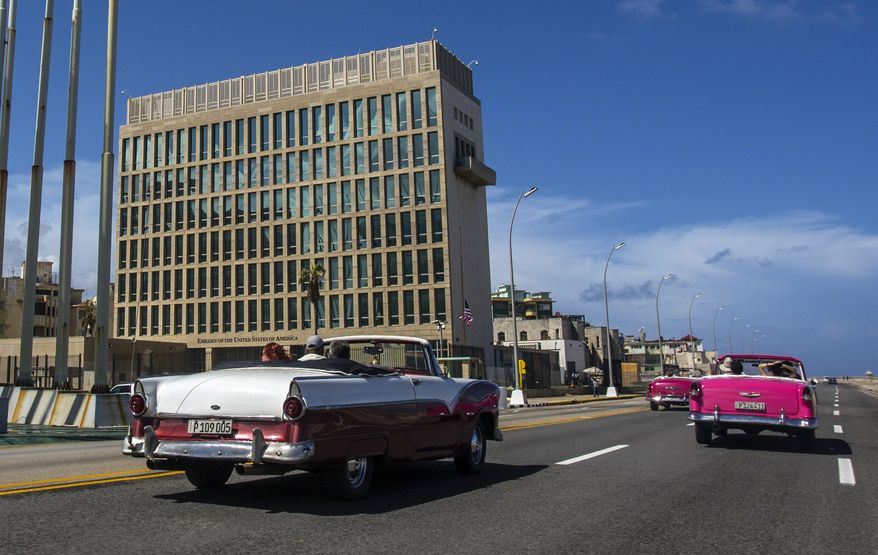In this Oct. 3, 2017, photo, tourists ride classic convertible cars on the Malecon beside the U.S. Embassy in Havana, Cuba. The Biden administration faces increasing pressure to respond to a sharply growing number of reported injuries suffered by diplomats, intelligence officers and military personnel that some suspect are caused by devices that emit waves of energy that disrupt brain function. The problem has been labeled the “Havana Syndrome,” because the first cases affected personnel in 2016 at the U.S. Embassy in Cuba. (AP Photo/Desmond Boylan) **FILE**