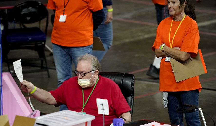In this May 6, 2021 file photo, Maricopa County ballots cast in the 2020 general election are examined and recounted by contractors working for Florida-based company, Cyber Ninjas at Veterans Memorial Coliseum in Phoenix. (AP Photo/Matt York, Pool)  **FILE**