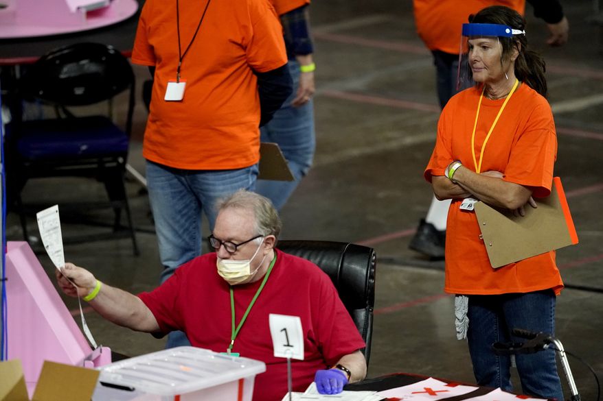 In this May 6, 2021 file photo, Maricopa County ballots cast in the 2020 general election are examined and recounted by contractors working for Florida-based company, Cyber Ninjas at Veterans Memorial Coliseum in Phoenix. (AP Photo/Matt York, Pool) **FILE**