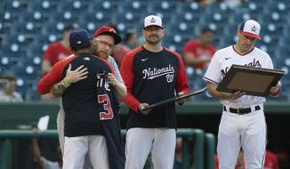 Cincinnati Reds&#39; Sean Doolittle hugs his manager from the 2019 World Series champion Washington Nationals, Dave Martinez, as he is acknowledged on the field by his former team during a baseball game beaten the Reds and Nationals in Washington, Tuesday, May 25, 2021. Nationals&#39; Daniel Hudson and Ryan Zimmerman, right, hold plaques. (AP Photo/Manuel Balce Ceneta)