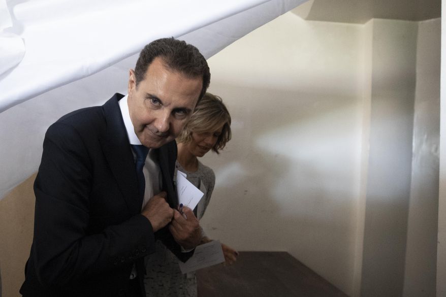 Syrian President Bashar Assad and his wife Asma prepare to vote at a polling station during the Presidential elections in the town of Douma, in the eastern Ghouta region, near the Syrian capital Damascus, Syria, Wednesday, May 26, 2021. Syrians headed to polling stations early Wednesday to vote in the second presidential elections since the deadly conflict began in the Arab country. (AP Photo/Hassan Ammar)