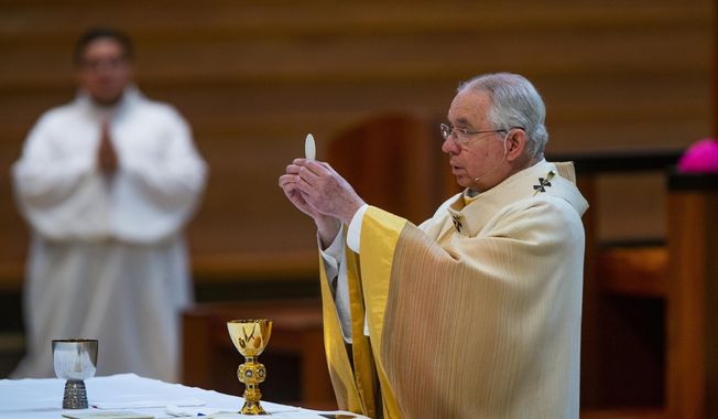 In this Sunday, June 7, 2020, file photo, Archbishop Jose H. Gomez holds a Communion wafer as he celebrates the Solemnity of the Most Holy Trinity, a Mass, with churchgoers present at the Cathedral of Our Lady of the Angels in downtown Los Angeles. The U.S. Conference of Catholic Bishops plans to devote part of its national meeting in June 2021 to the sensitive issue of which Catholics are worthy of receiving Communion. (AP Photo/Damian Dovarganes, File)