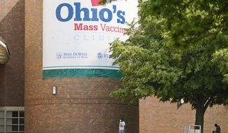 People walk past sign displayed for Ohio&#39;s COVID-19 mass vaccination clinic at Cleveland State University, Tuesday, May 25, 2021, in Cleveland. Nearly 2.8 million residents have registered for Ohio&#39;s Vax-a-Million vaccination incentive program, with participants hoping to win either the $1 million prize for adults or a full-ride college scholarship for children, Gov. Mike DeWine announced Monday, May 24. The winners will be announced Wednesday night at the end of the Ohio Lottery&#39;s Cash Explosion TV show, and then each Wednesday for the next four weeks. (AP Photo/Tony Dejak)