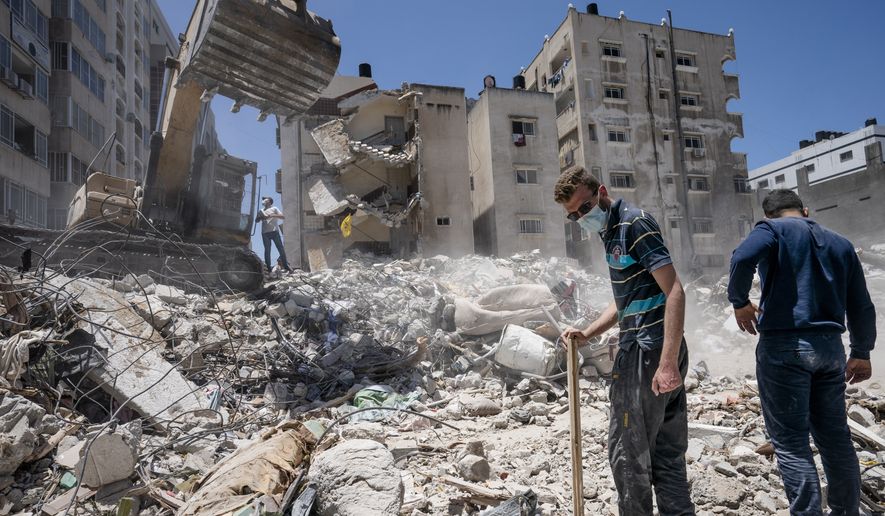 Heavy construction equipment is used to sift through rubble to uncover valuables before it is transported away from the scene of a building destroyed in an airstrike prior to a cease-fire that halted an 11-day war between Gaza&#x27;s Hamas rulers and Israel, Thursday, May 27, 2021, in Gaza City. (AP Photo/John Minchillo)