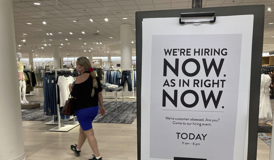 A customer walks behind a sign at a Nordstrom store seeking employees, Friday, May 21, 2021, in Coral Gables, Fla. The number of Americans seeking unemployment benefits dropped last week to 406,000, a new pandemic low and more evidence that the job market is strengthening as the virus wanes and economy further reopens. (AP Photo/Marta Lavandier)