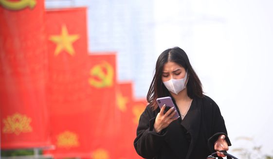 In this Jan. 23, 2021, file photo, a woman wearing a face mask looks at her phone in Hanoi, Vietnam. Vietnam says it has discovered a new coronavirus variant that’s a hybrid of strains first found in India and the U.K. The Vietnamese health minister made the announcement Saturday, May 29. (AP Photo/Hau Dinh, File)