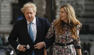 British Prime Minister Boris Johnson arrives at a polling station with his partner Carrie Symonds to cast his vote in local council elections in London.  (AP Photo/Matt Dunham, File)