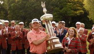 Jason Kokrak poses with the Leonard Trophy after winning the Charles Schwab Challenge golf tournament at the Colonial Country Club in Fort Worth, Texas Sunday, May 30, 2021, as Colonial Country Club president Christine Klote, right, and other applaud him.(AP Photo/Michael Ainsworth)