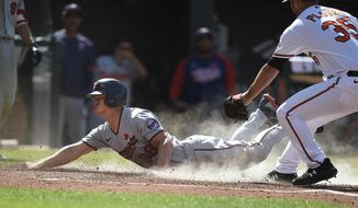 Minnesota Twins&#39; Rob Refsnyder, left, slides across the plate as Baltimore Orioles pitcher Adam Plutko covers in the 10th inning of a baseball game Monday, May 31, 2021, in Baltimore. Refsnyder was safe, scoring the go-ahead run on a wild pitch. (AP Photo/Gail Burton)