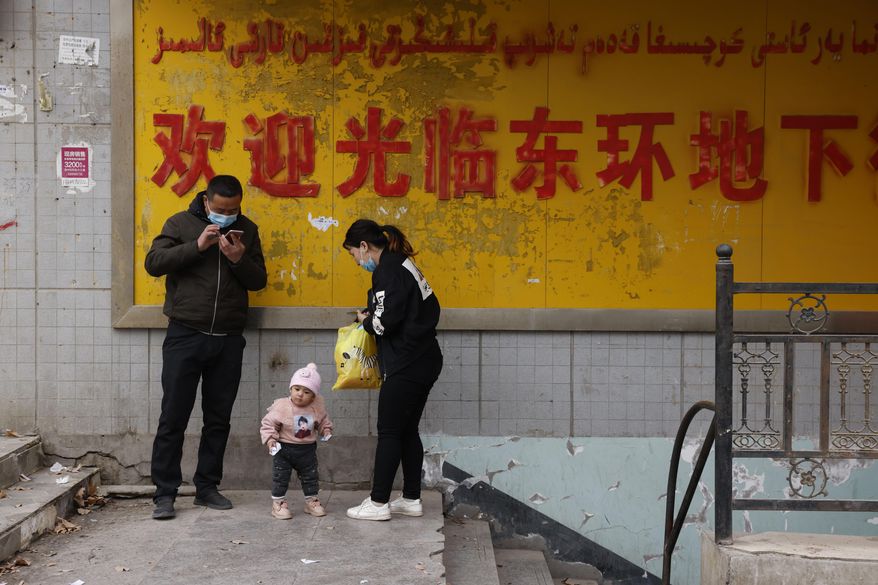 A family stands at the entrance to an underground retail street in Aksu in western China's Xinjiang Uyghur Autonomous Region on March 18, 2021. The U.S. State Department on July 13 released a report documenting human rights abuses targeting the Uyghurs. (AP Photo/Ng Han Guan)