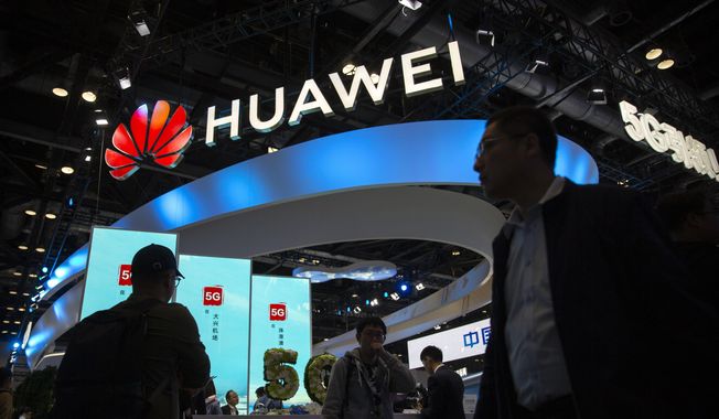 In this Oct. 31, 2019, file photo, attendees walk past a display for 5G services from Chinese technology firm Huawei at the PT Expo in Beijing. U.S. President Joe Biden has nearly doubled the list of Chinese companies whose shares are off-limits to U.S. investors in the latest sign he is not softening Washington&#x27;s stance toward Beijing. Telecoms equipment maker Huawei Technologies, China鈥檚 big state-owned telecoms companies and China National Offshore Oil Corp. are on the new list of 59 companies. (AP Photo/Mark Schiefelbein, File) **FILE**