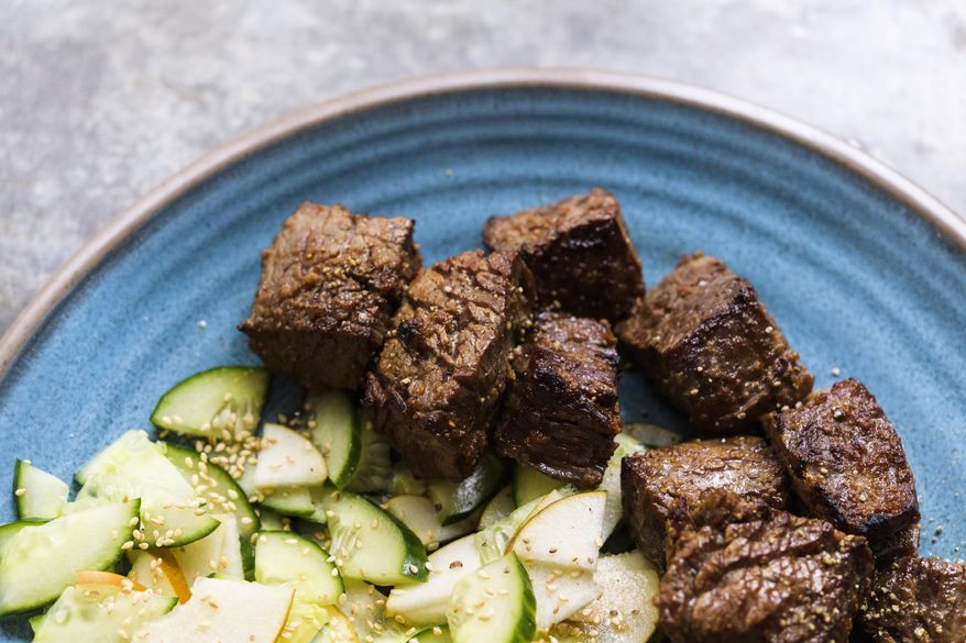 This image released by Milk Street shows a recipe for Ginger-Soy Steak with Pear-Cucumber Salad. Sirloin tips cut into quick-cooking chunks offer greater surface area, making it easy to add flavor with a gingery marinade. A salty soy sauce ensures the meat absorbs as much flavor as possible. (Milk Street via AP)