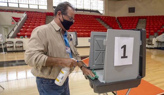 Poll worker Phil Dingus cleans one of the voting machines at the Virginia High School precinct during the Virginia Democratic Primary Election, on Tuesday, June 8, 2021, in Bristol, Va. (David Crigger/Bristol Herald Courier via AP) ** FILE **