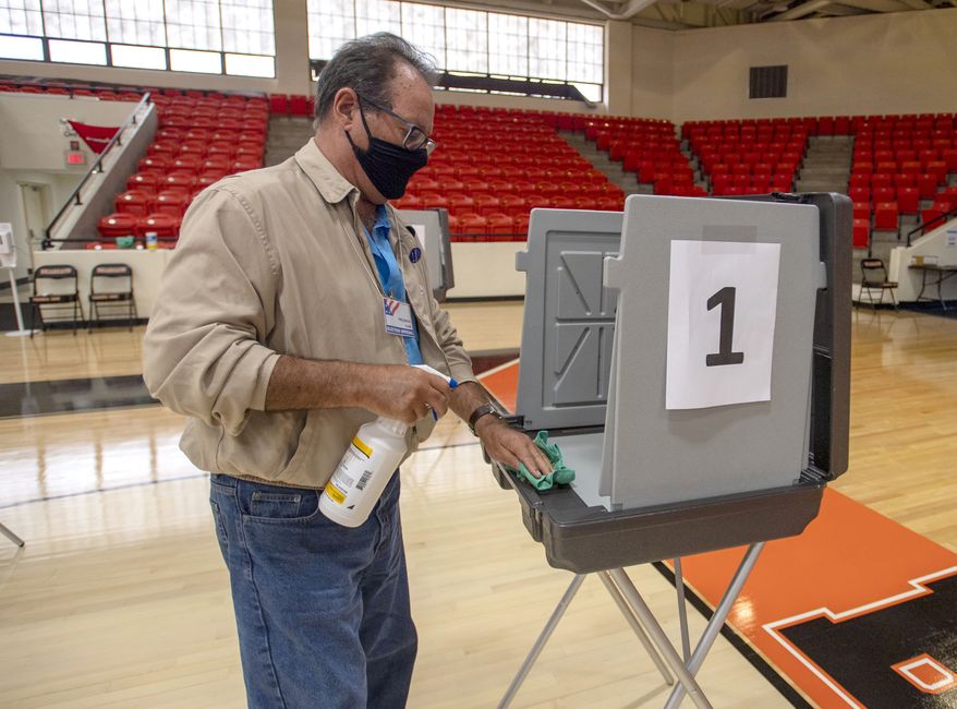 Poll worker Phil Dingus cleans one of the voting machines at the Virginia High School precinct during the Virginia Democratic Primary Election, on Tuesday, June 8, 2021, in Bristol, Va. (David Crigger/Bristol Herald Courier via AP) ** FILE **