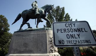 In this Aug. 6, 2018, file photo, a No Trespassing sign is displayed in front of a statue of Confederate Gen. Robert E. Lee in Charlottesville, Va. Charlottesville officials have voted unanimously to remove two statues of Confederate generals Robert E. Lee and Stonewall Jackson from two downtown parks including one that was the focus of a violent white nationalist rally in 2017.   News outlets report that the vote came late Monday, June 7, 2021, after more than 50 people spoke during a virtual meeting, most in favor of removal.   (AP Photo/Steve Helber, File)