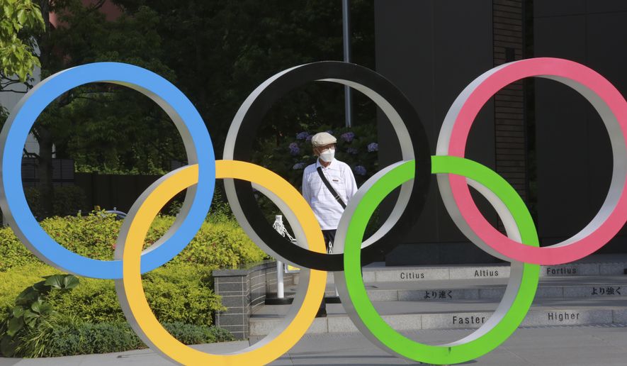A man walks past the Olympic rings in Tokyo, Monday, June 7, 2021. (AP Photo/Koji Sasahara) **FILE**