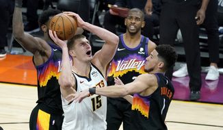 Denver Nuggets center Nikola Jokic (15) shoots over Phoenix Suns guard Devin Booker (1) during Game 1 of an NBA basketball second-round playoff series, Monday, June 7, 2021, in Phoenix. (AP Photo/Matt York) **FILE**