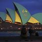 In this Friday, Aug. 5, 2016, file photo, a couple sit on a dock to look at the sails of the Sydney Opera House that are illuminated with the green and gold colors of the Australian Olympic team, as Australia pushes to host the 2032 Olympics.  Brisbane will be offered as the 2032 Olympics host, IOC president Thomas Bach said Thursday June 10, 2021, for International Olympic Committee members to confirm in Tokyo next month. (AP Photo/Rick Rycroft, File) **FILE**