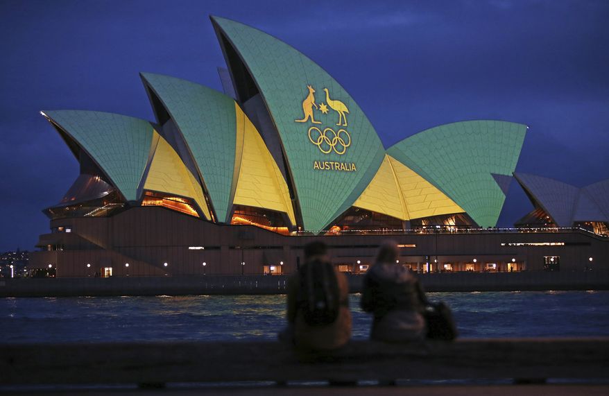 In this Friday, Aug. 5, 2016, file photo, a couple sit on a dock to look at the sails of the Sydney Opera House that are illuminated with the green and gold colors of the Australian Olympic team, as Australia pushes to host the 2032 Olympics.  Brisbane will be offered as the 2032 Olympics host, IOC president Thomas Bach said Thursday June 10, 2021, for International Olympic Committee members to confirm in Tokyo next month. (AP Photo/Rick Rycroft, File) **FILE**