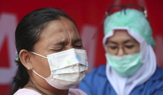 A woman receives the AstraZeneca vaccine during a mass coronavirus vaccination for public transport workers at the Kampung Rambutan Bus Terminal in Jakarta, Indonesia, Thursday, June 10, 2021. (AP Photo/Achmad Ibrahim)