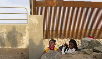 A Haitian migrant family looks to emerge from a rocky canal adjacent to a gap in the U.S. border wall in Yuma, Ariz., Wednesday, June 9, 2021. (AP Photo/Eugene Garcia)