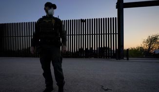 A U.S. Customs and Border Protection agent looks on near a gate on the U.S.-Mexico border wall as agents take migrants into custody, in Abram-Perezville, Texas, March 21, 2021. (AP Photo/Julio Cortez) ** FILE **