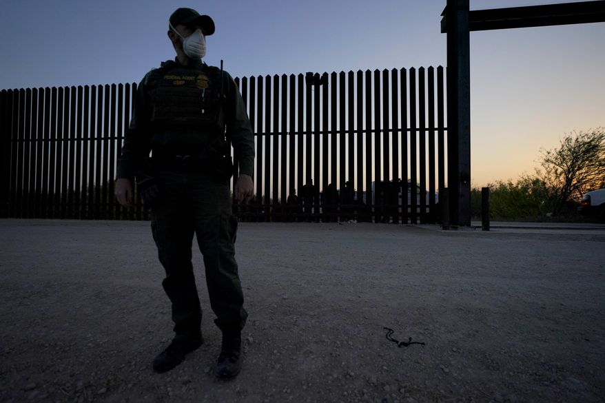 A U.S. Customs and Border Protection agent looks on near a gate on the U.S.-Mexico border wall as agents take migrants into custody, in Abram-Perezville, Texas, March 21, 2021. (AP Photo/Julio Cortez) ** FILE **
