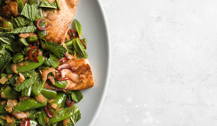This image released by Milk Street shows a recipe for salmon with chilies, pickled ginger and snap peas. (Milk Street via AP)