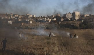 Israeli soldiers use teargas to disperse Palestinian protesters during clashes at the entrance the Jewish settlement of Beit El, near the West Bank city of Ramallah, background, Tuesday, June. 15, 2021. (AP Photo/Nasser Nasser)