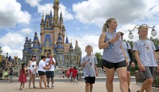 Guests walk past Cinderella Castle at the Magic Kingdom at Walt Disney World, in Lake Buena Vista, Fla. (Joe Burbank/Orlando Sentinel via AP)