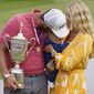 Jon Rahm, of Spain, holds the champions trophy for photographers as he stands with his wife, Kelley Rahm and kisses their child, Kepa Rahm, 11 months, after the final round of the U.S. Open Golf Championship, Sunday, June 20, 2021, at Torrey Pines Golf Course in San Diego. (AP Photo/Marcio Jose Sanchez) **FILE**