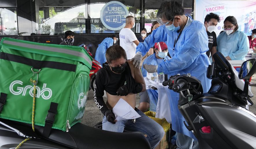 A motorcycle delivery driver is inoculated with China&#39;s Sinovac COVID-19 vaccine at a drive-thru vaccination center in Manila, Philippines, Tuesday, June 22, 2021. The Philippine president has threatened to order the arrest of Filipinos who refuse COVID-19 vaccination and told them to leave the country for hard-hit countries like India and the United States if they would not cooperate with massive efforts to end the pandemic. (AP Photo/Aaron Favila)