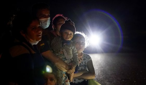 In this May 17, 2021, photo, a group of migrants mainly from Honduras and Nicaragua wait along a road after turning themselves in upon crossing the U.S.-Mexico border, in La Joya, Texas. The U.S. Homeland Security Department says thousands of asylum-seekers whose claims were dismissed or denied under a Trump administration policy that forced them to wait in Mexico for their court hearings will be allowed to return for another chance at humanitarian protection. (AP Photo/Gregory Bull) **FILE**