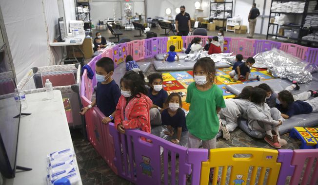 In this March 30, 2021, photo, young unaccompanied migrants, from ages 3 to 9, watch television inside a playpen at the U.S. Customs and Border Protection facility, the main detention center for unaccompanied children in the Rio Grande Valley, in Donna, Texas. On Monday, June 21, 2021, more than a dozen immigrant children described difficult conditions, feelings of isolation and a desperation to get out of emergency facilities set up by the Biden administration to cope with a rise in the arrival of minors on the southwest border. (AP Photo/Dario Lopez-Mills, Pool) ** FILE **