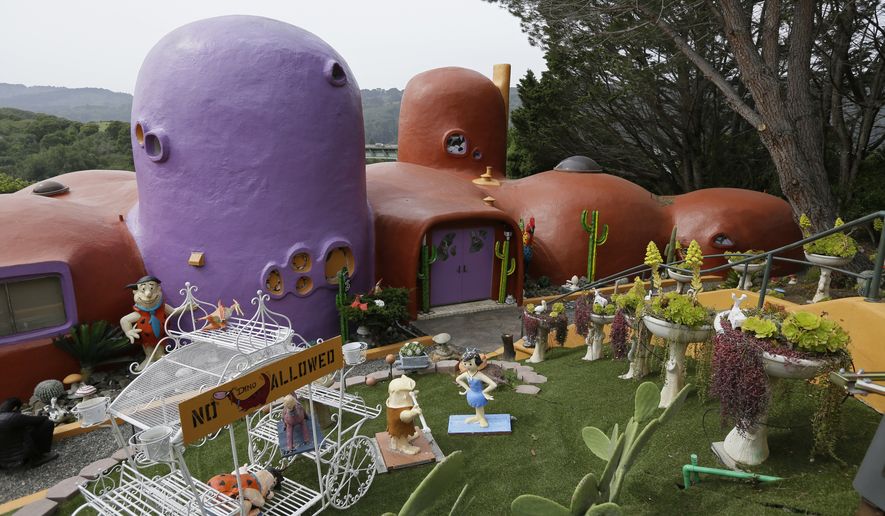 FILE - In this Thursday, April 11, 2019, file photo, The Flintstone House is seen before a news conference with the owner and the home&#39;s original architect in Hillsborough, Calif. The San Francisco Bay Area suburb of Hillsborough is suing the owner of the house, saying that she installed dangerous steps, dinosaurs and other Flintstone-era figurines without necessary permits. In a yabba dabba dispute that pitted property rights against government rules that played out in international media, retired publishing mogul Florence Fang defended her colorful, bulbous-shaped house and its elaborate homage to &quot;The Flintstones&quot; family, featuring Stone Age sculptures inspired by the 1960s cartoon, along with aliens and other oddities. (AP Photo/Eric Risberg, File)