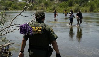 A Border Patrol agent watches as a group of migrants walk across the Rio Grande on their way to turn themselves in upon crossing the U.S.-Mexico border, Tuesday, June 15, 2021, in Del Rio, Texas. U.S. government data shows that 42% of all families encountered along the border in May hailed from places other than Mexico, El Salvador, Guatemala and Honduras  the traditional drivers of migratory trends. (AP Photo/Eric Gay)