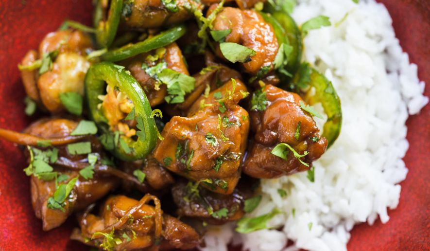 This image released by Milk Street shows a recipe for caramel chicken, made with shallots, ginger and a jalapeño chili. (Milk Street via AP)