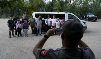 A group of migrants, mostly from Venezuela are photographed after turning themselves in after crossing the U.S.-Mexico border, Tuesday, June 15, 2021, in Del Rio, Texas. Many of the migrants cross during daylight, looking to turn themselves in to Border Patrol agents who document their arrival. (AP Photo/Eric Gay)